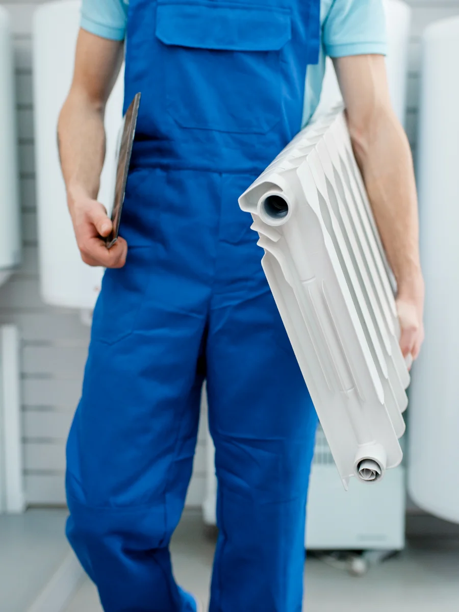 Handwerker im Laden mit einem Heizkörper im Arm