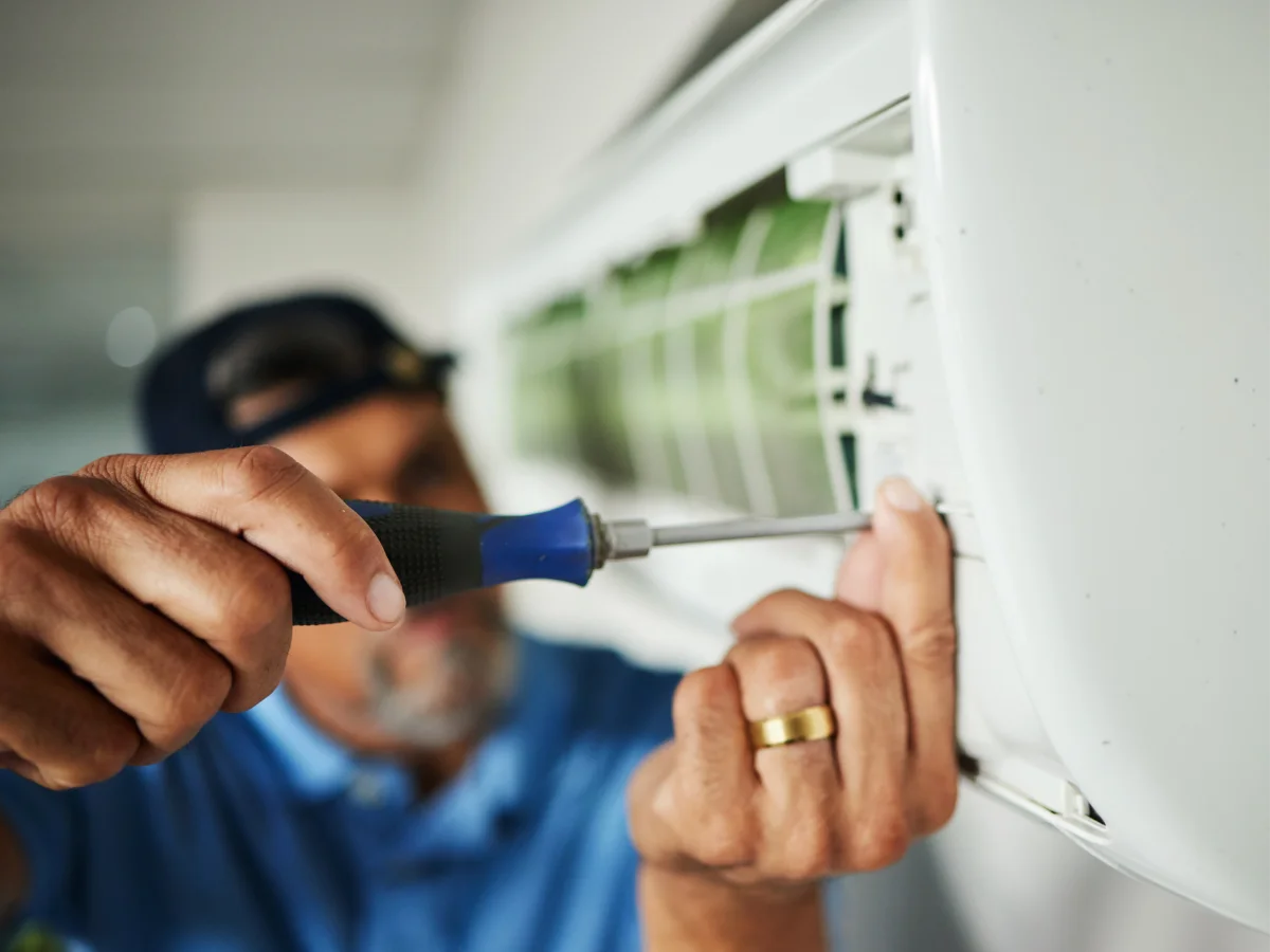 Techniker schraubt an einer Klimaanlage